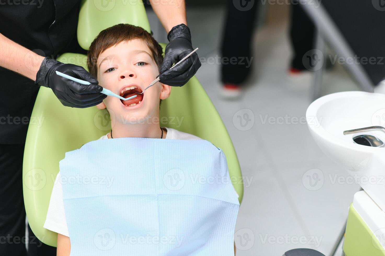 Cute boy smiling while teeth exam . Happy boy sitting in dentists chair and having check up teeth photo