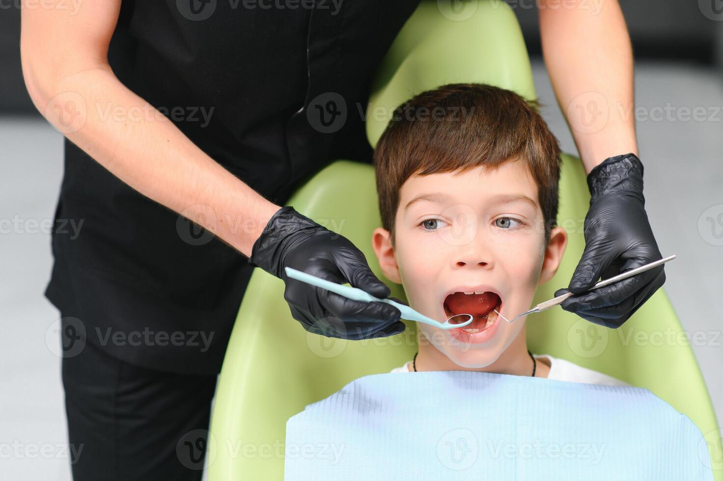 Cute boy smiling while teeth exam . Happy boy sitting in dentists chair and having check up teeth photo