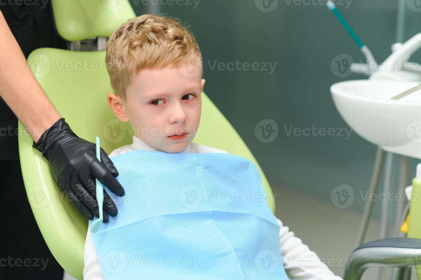 Scared red-haired boy crying at reception at dentist in dental chair. Pediatric dentistry photo