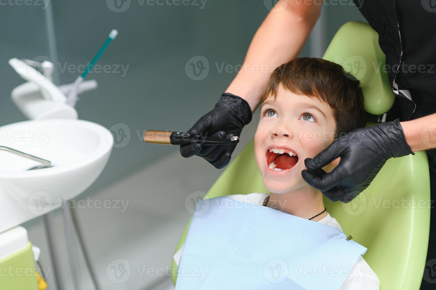 Dentist examining little boy's teeth in clinic photo