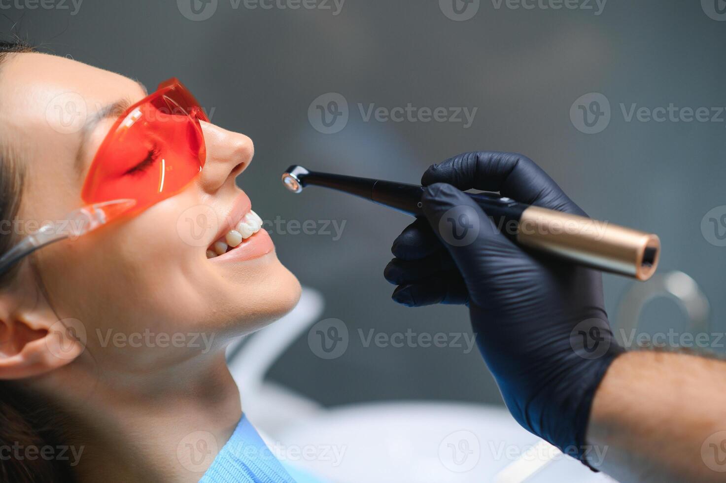 dentist curing the patient's teeth with ultraviolet lamp in his office photo