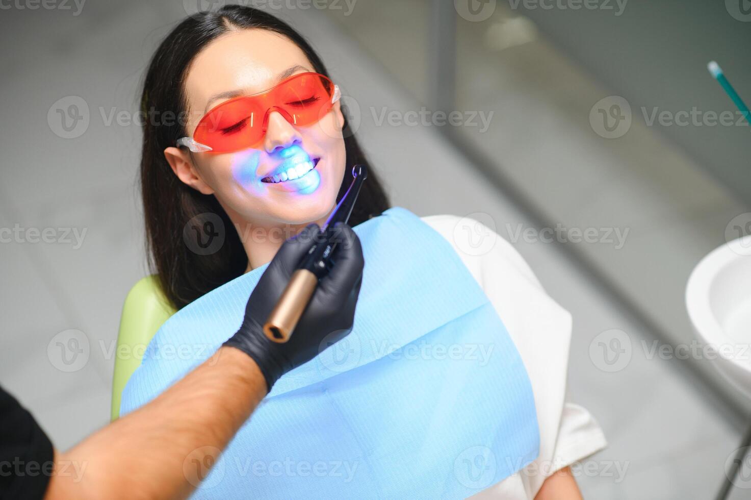 dentist curing the patient's teeth with ultraviolet lamp in his office photo