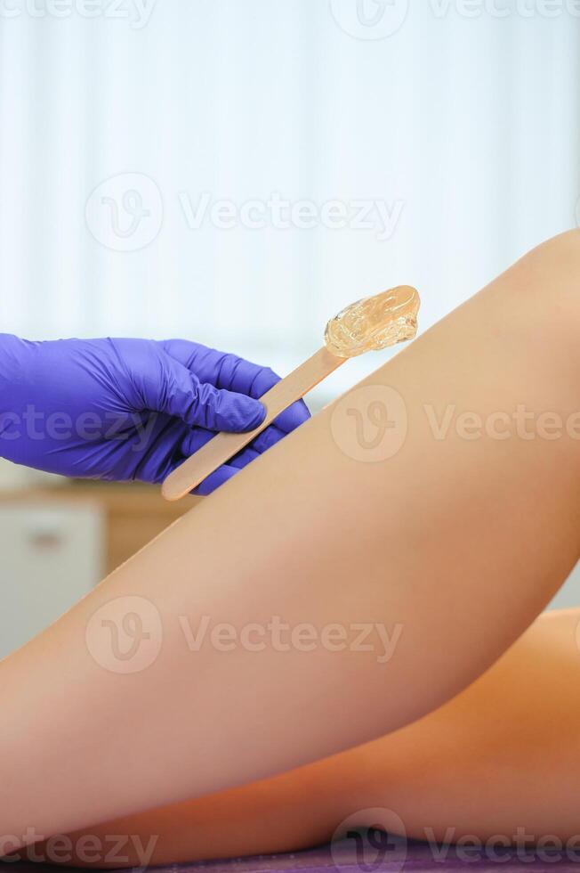 Sugaring epilation with liquate sugar at legs photo