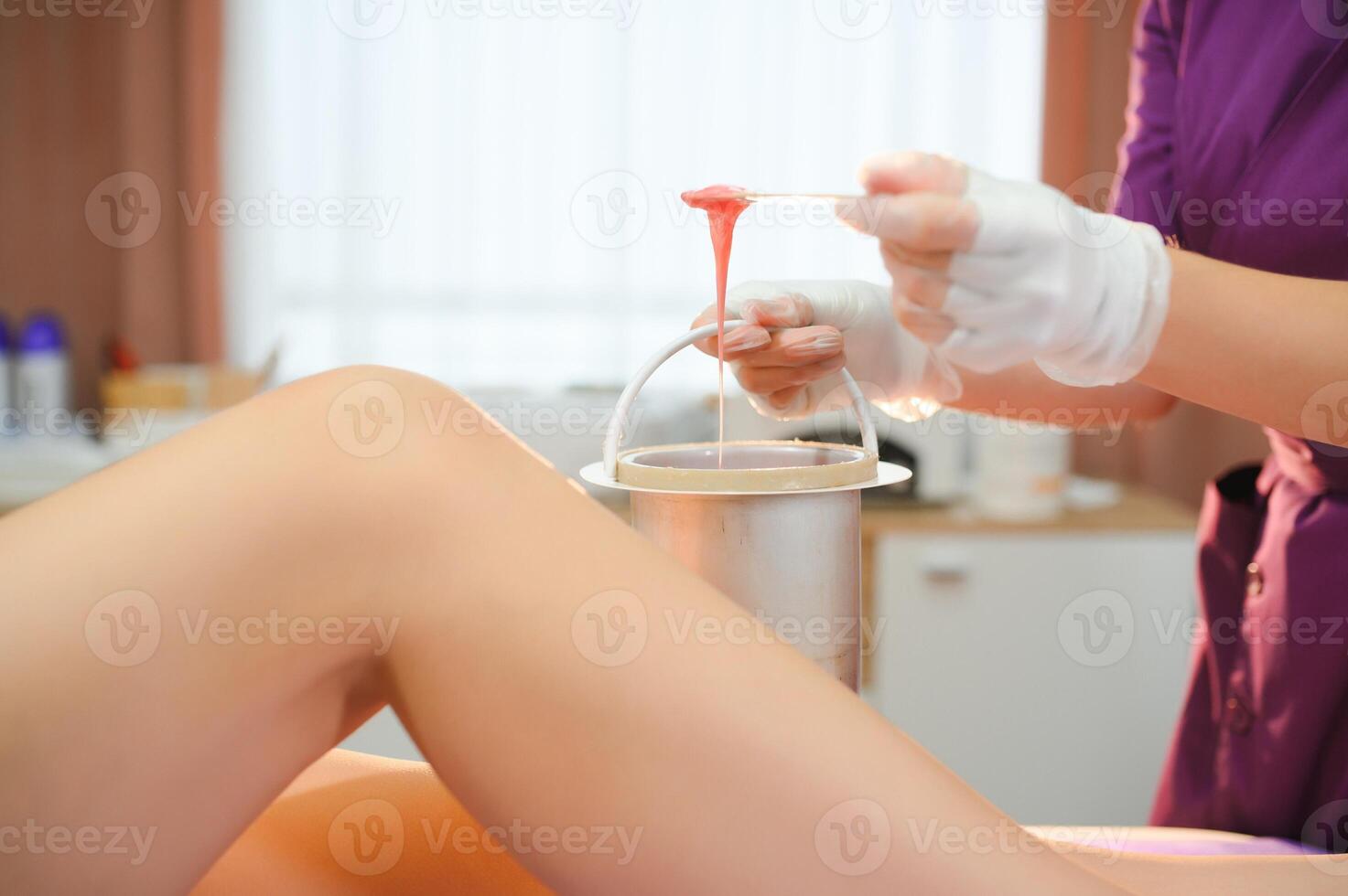 Woman having hair removal procedure on leg with sugaring paste in salon photo