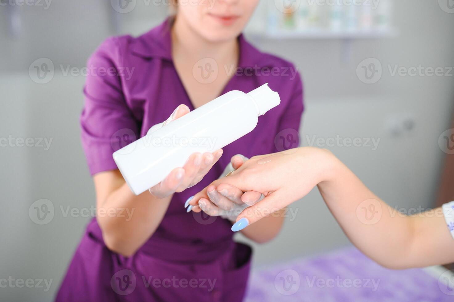 un cosmetólogo aplica crema a un clientela mano después depilación foto
