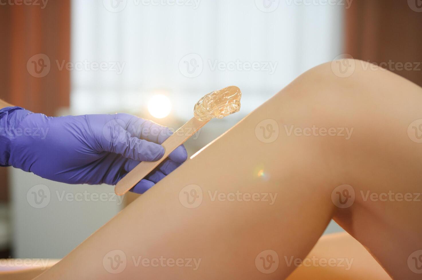 Woman having hair removal procedure on leg with sugaring paste in salon photo