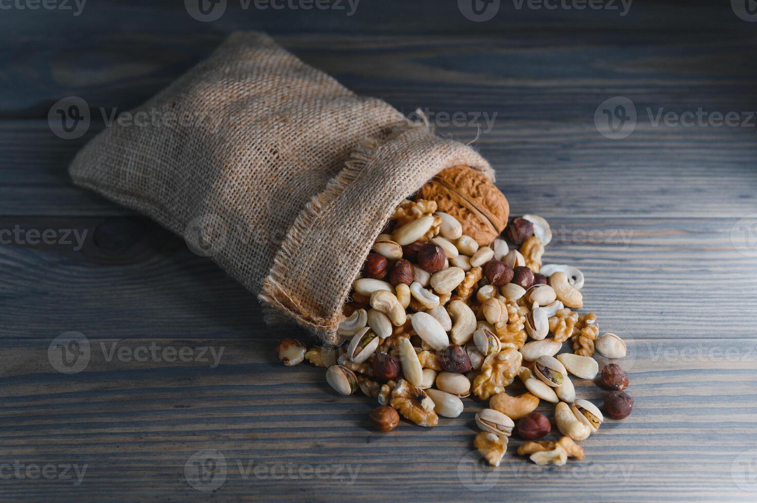 Wooden bowl with mixed nuts on rustic table top view. Healthy food and snack. photo