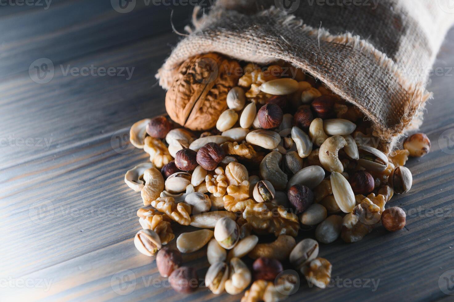 Wooden bowl with mixed nuts on rustic table top view. Healthy food and snack. photo