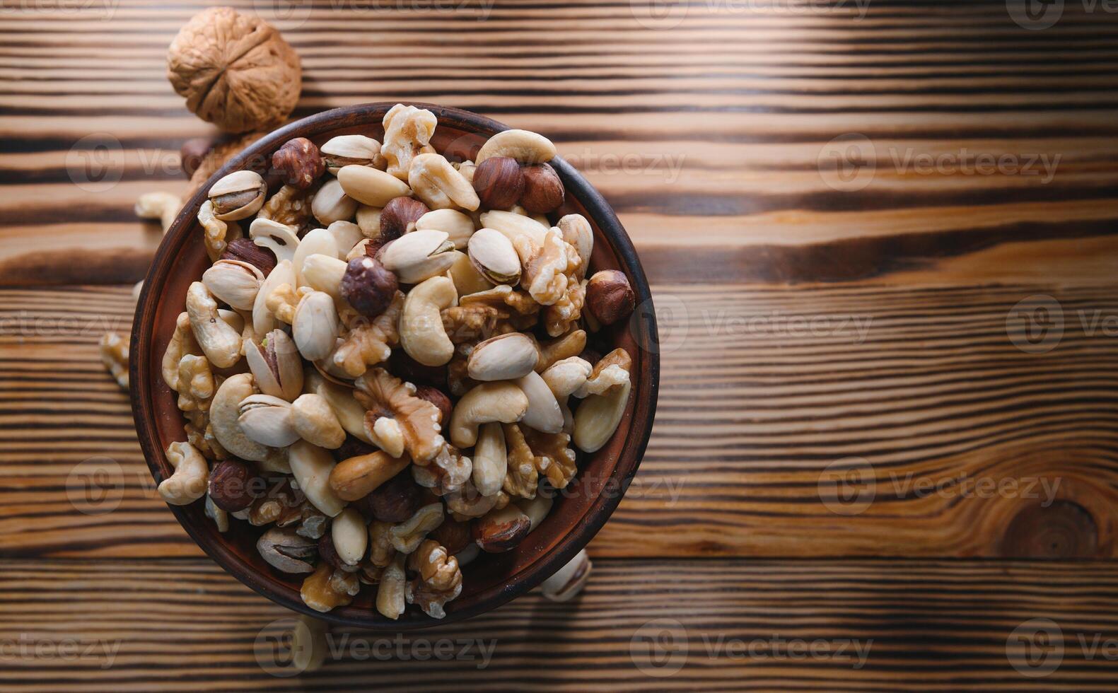 mixed nuts in a bowl on wooden table, top view with copy space. photo