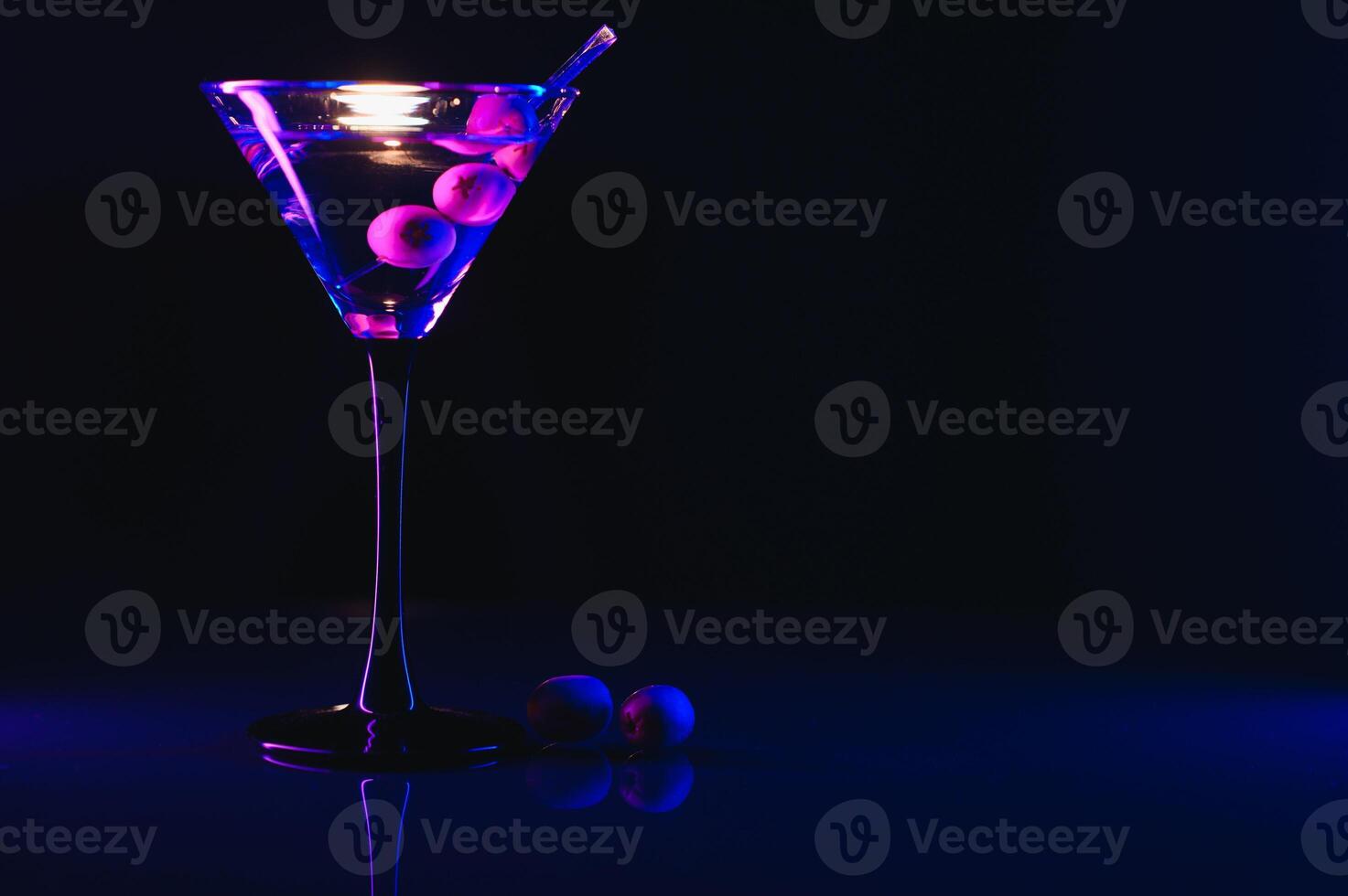 Glass of classic dry martini cocktail with olives on dark table against black background. With free space for your text photo