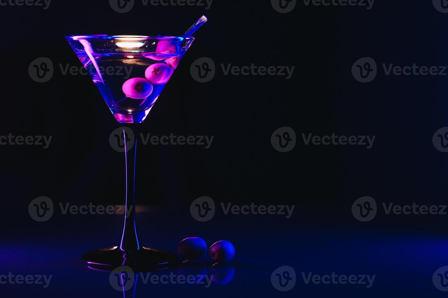 Martini glass and olives on a black background with neon lights photo