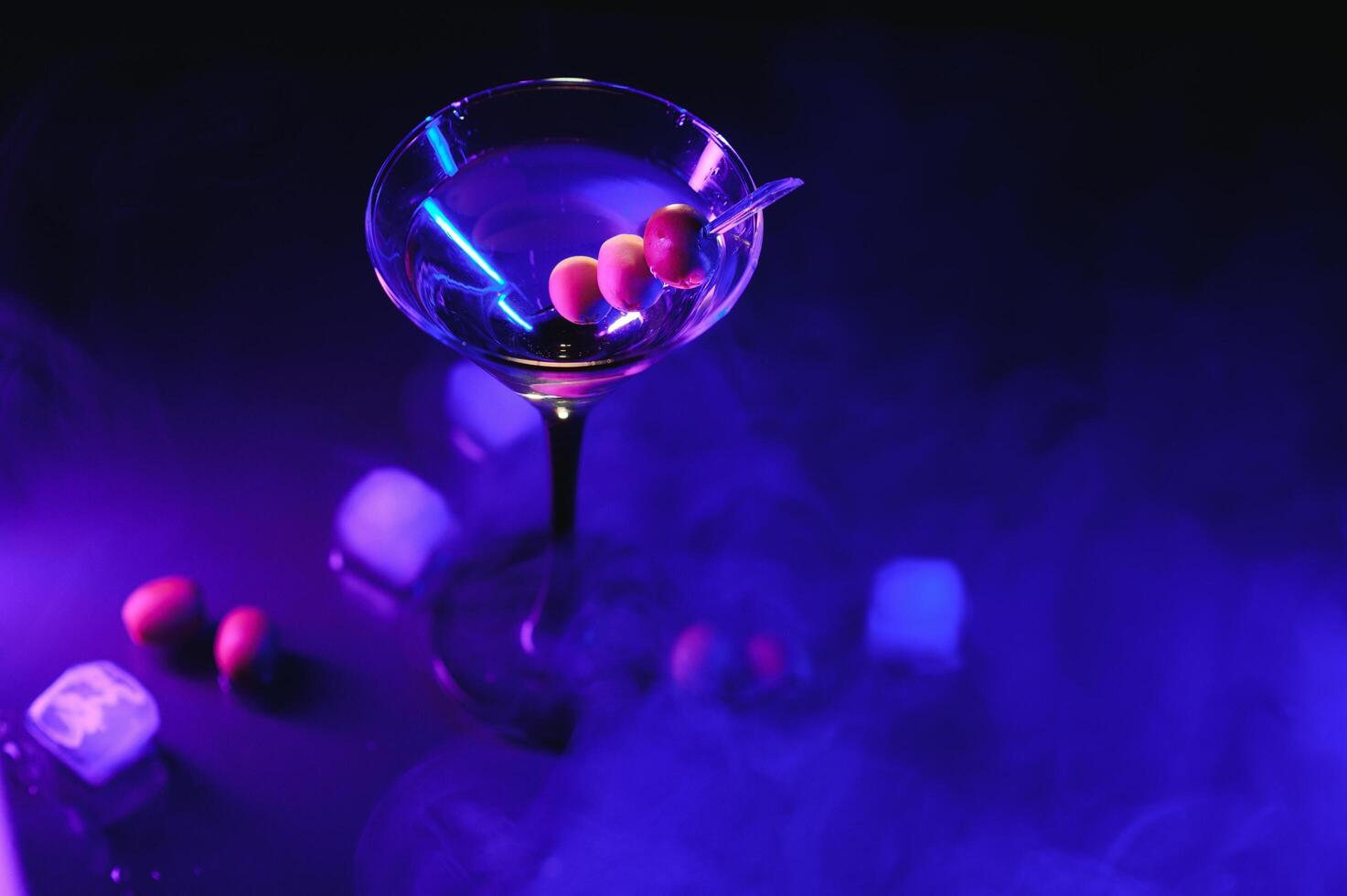 Glass of classic dry martini cocktail with olives on dark table against black background. With free space for your text photo