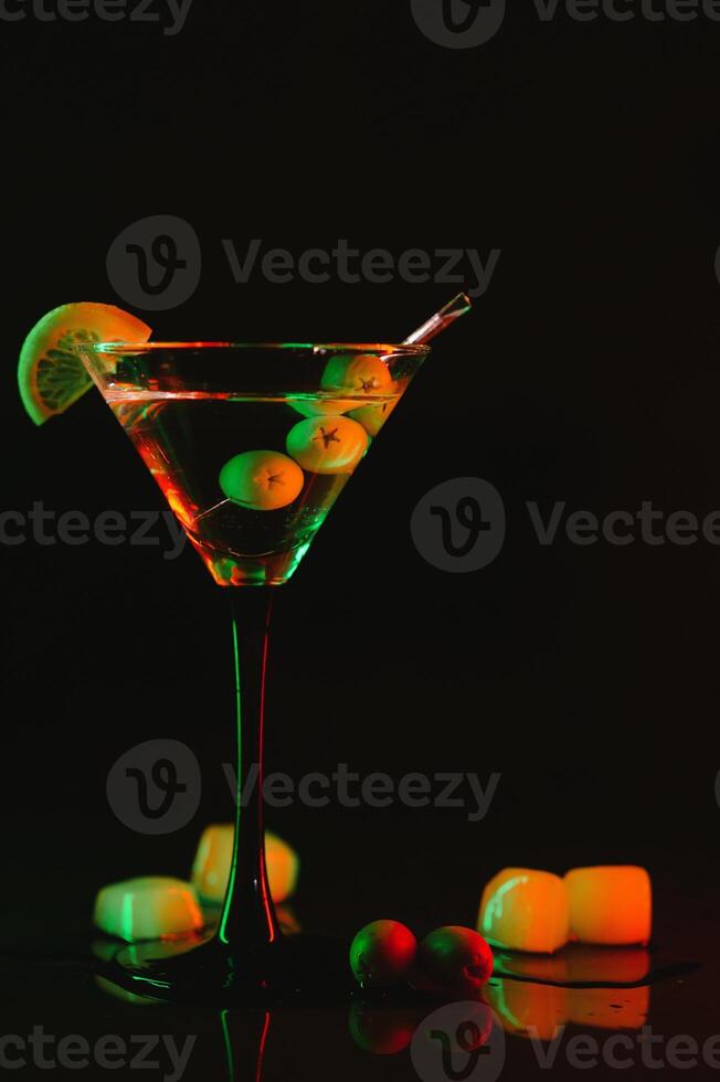 martini vaso y aceitunas en un negro antecedentes con neón luces foto