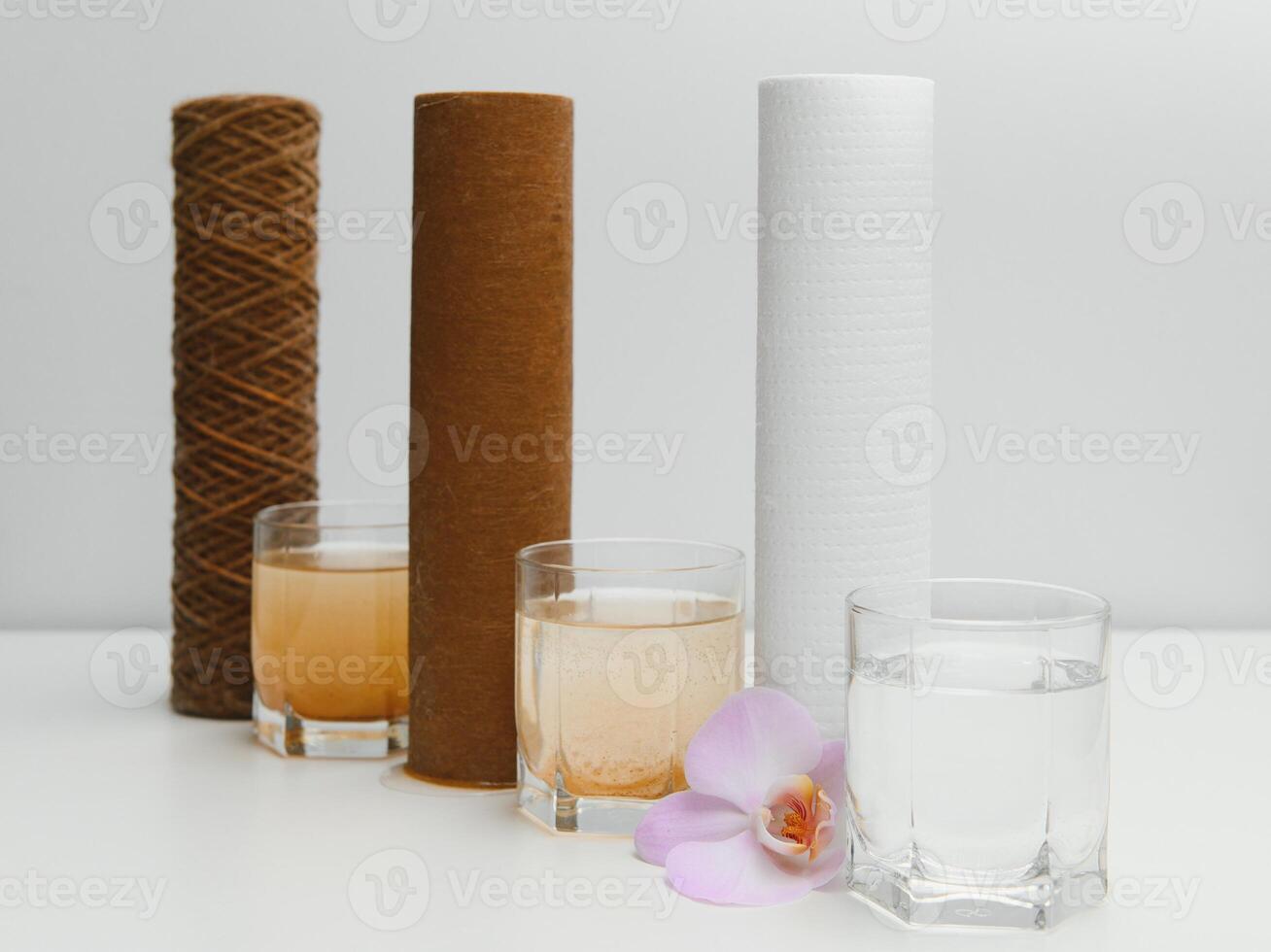 Water filters concept. Carbon cartridges and a three glasses on a white background. Household filtration system. photo