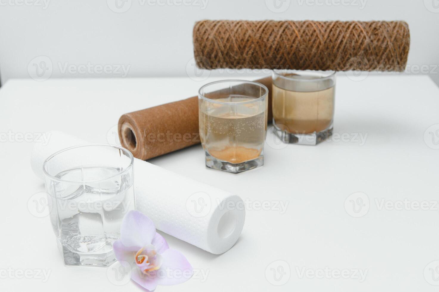 Filter system for water treatment with glasses of clean and dirty water on bright background photo