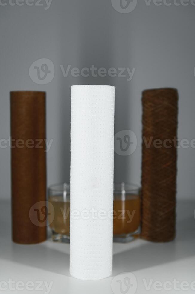 Water filters concept. Carbon cartridges and a three glasses on a white background. Household filtration system. photo