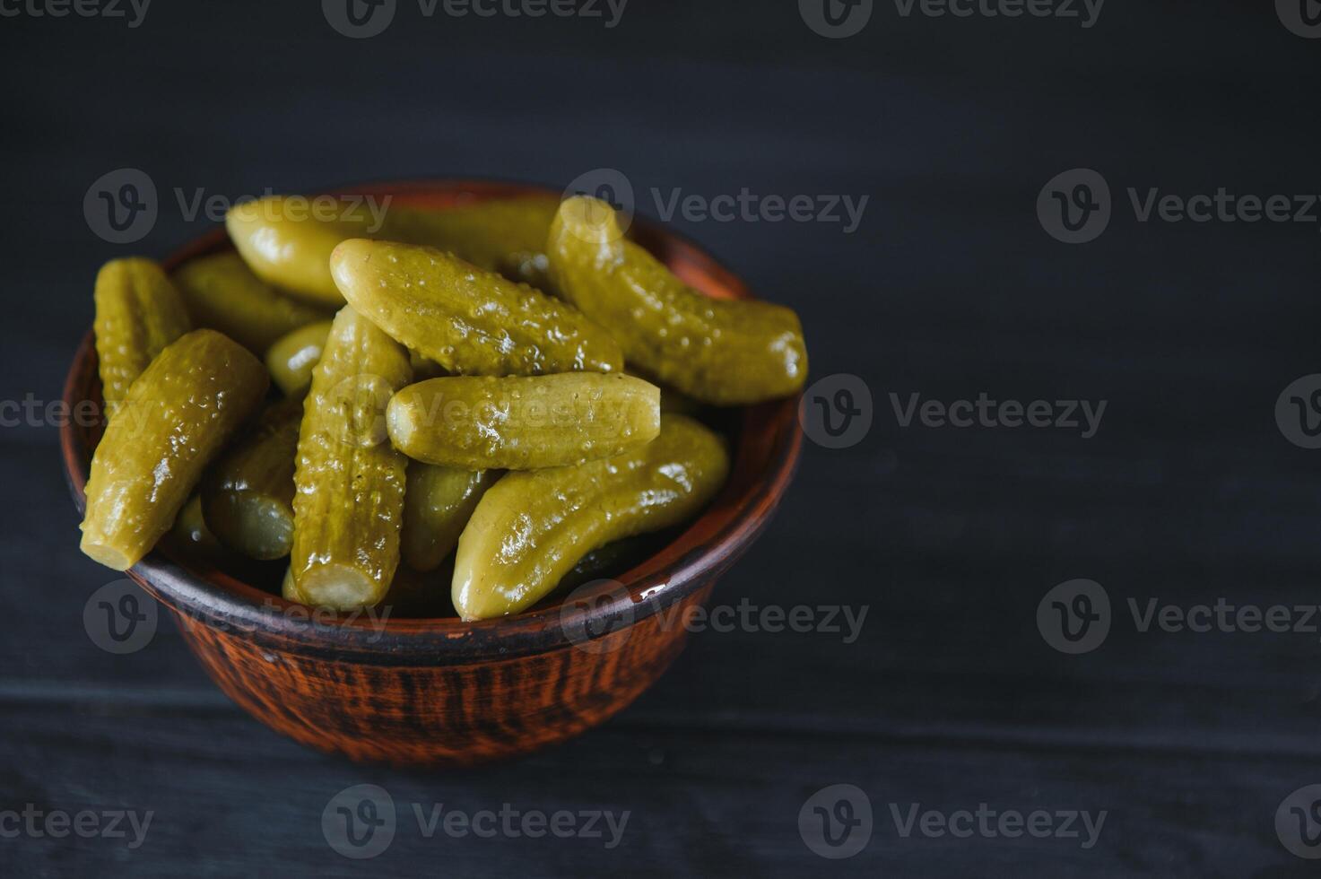 Pickled gherkins or cucumbers in bowl on wooden rustic table from above. photo