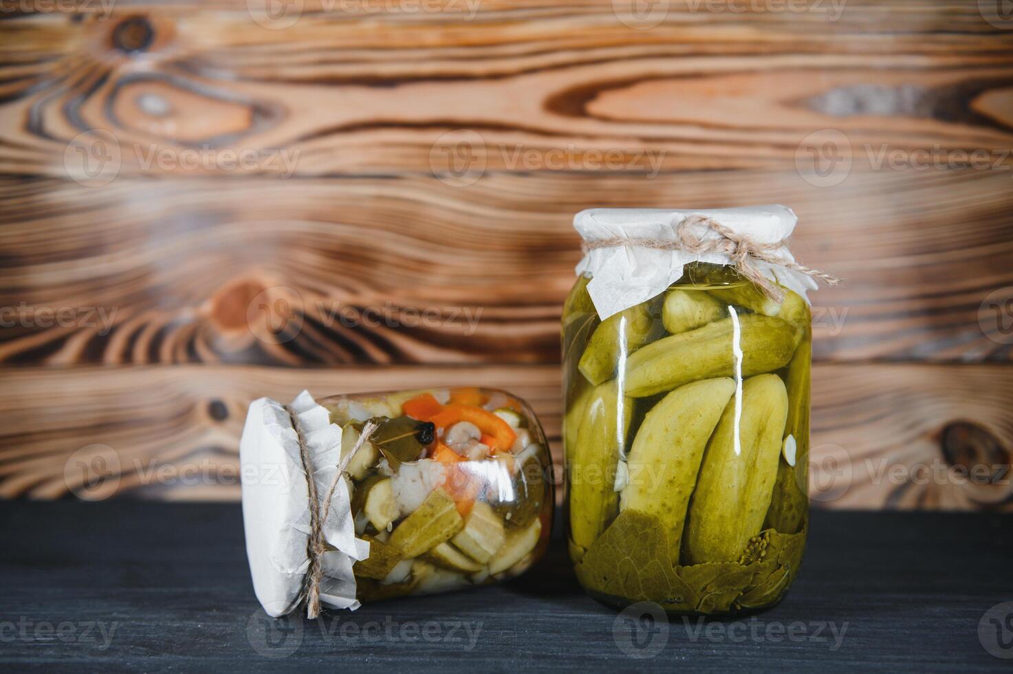 Jars of pickled vegetables on rustic wooden background photo