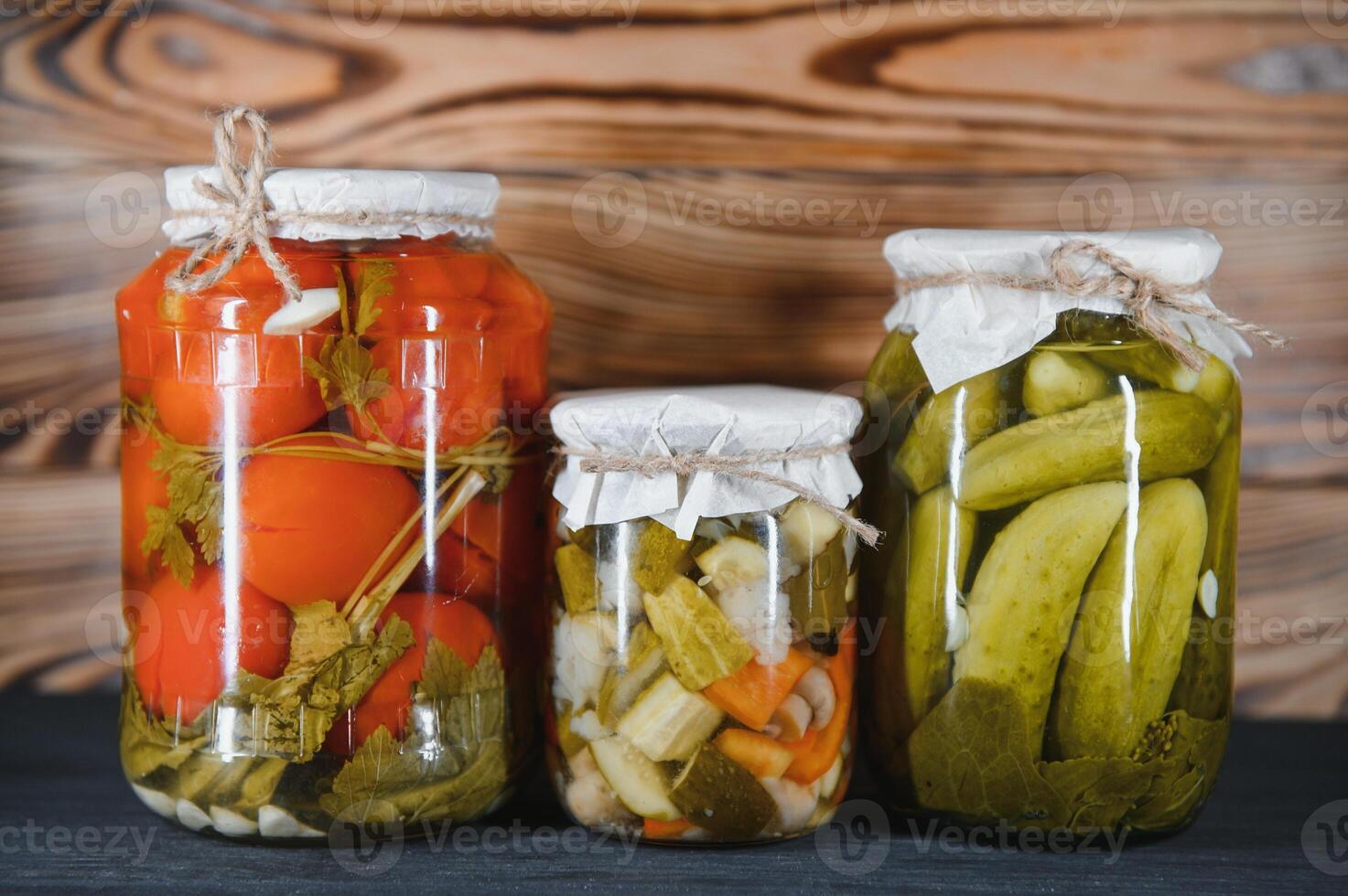Canned cucumbers and tomatoes with craft lids on a wooden background. Cucumbers and tomatoes with place for text. Stocks of canned food. Harvest, stocks for the winter. photo