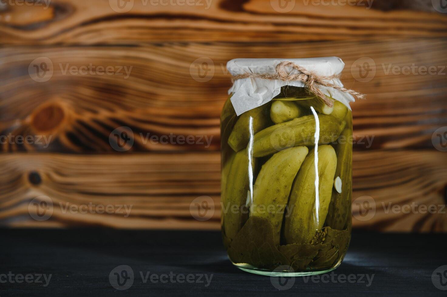 Pickled gherkins or cucumbers in bowl on wooden rustic table from above. photo