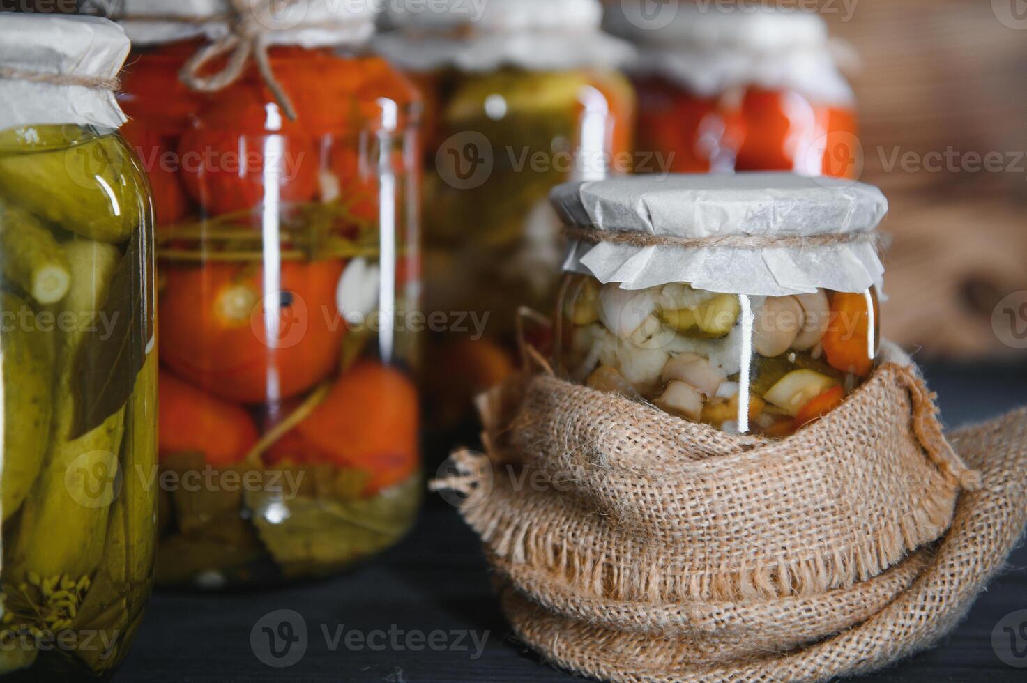 Jars of pickled vegetables on rustic wooden background photo