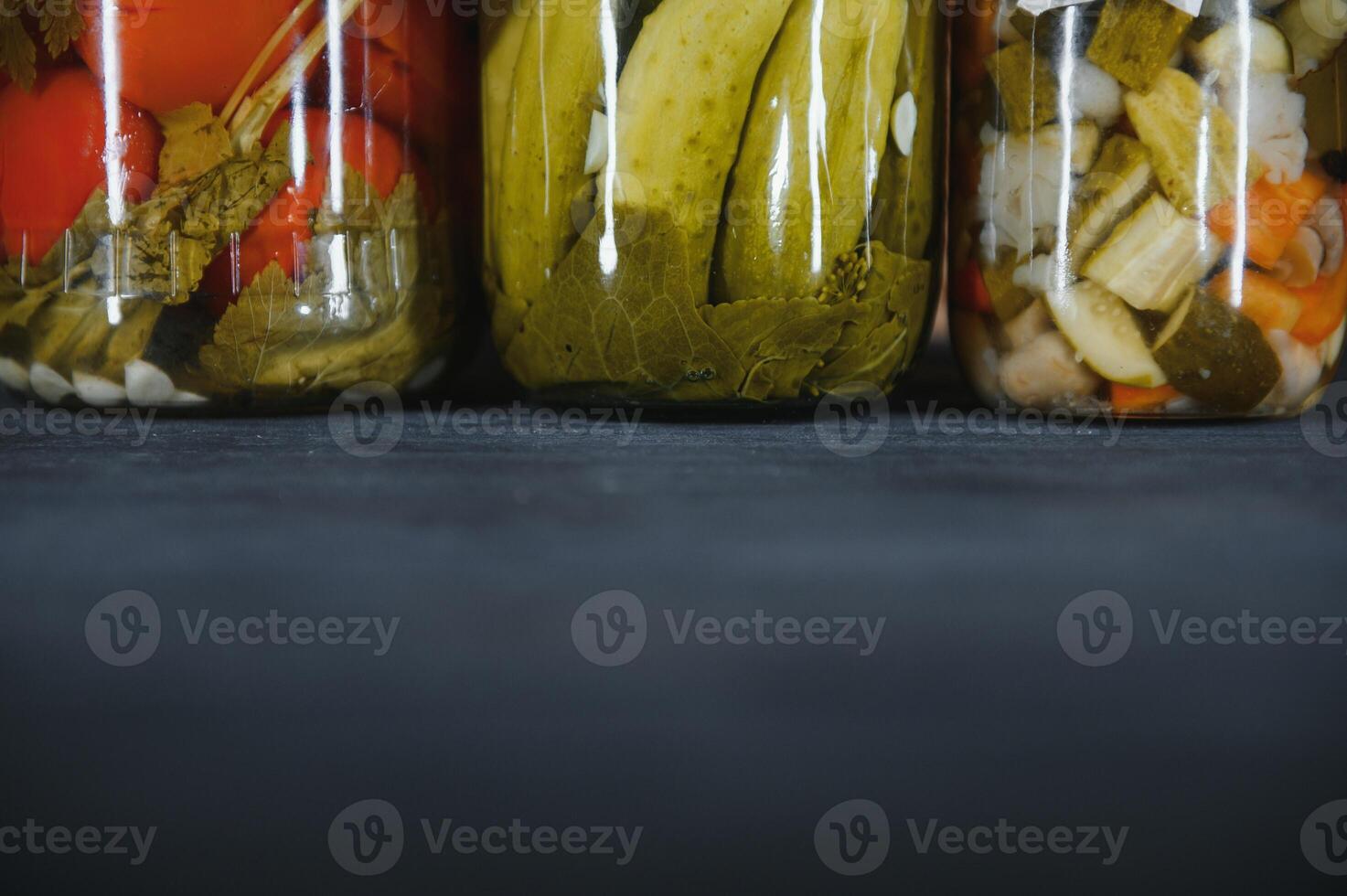 Glass jars with pickled cucumbers pickles, pickled tomatoes and cabbage. Jars of various pickled vegetables. Canned food in a rustic composition. photo