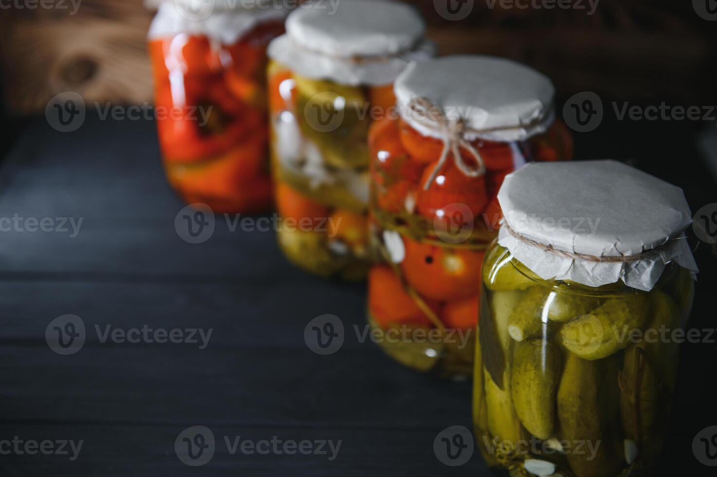 Canned cucumbers and tomatoes with craft lids on a wooden background. Cucumbers and tomatoes with place for text. Stocks of canned food. Harvest, stocks for the winter. photo