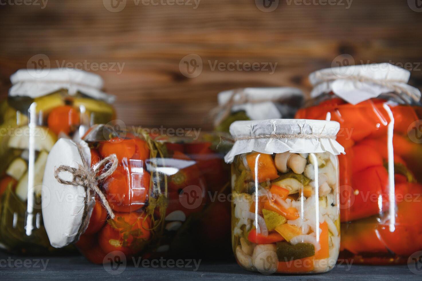 Glass jars with pickled cucumbers pickles, pickled tomatoes and cabbage. Jars of various pickled vegetables. Canned food in a rustic composition. photo