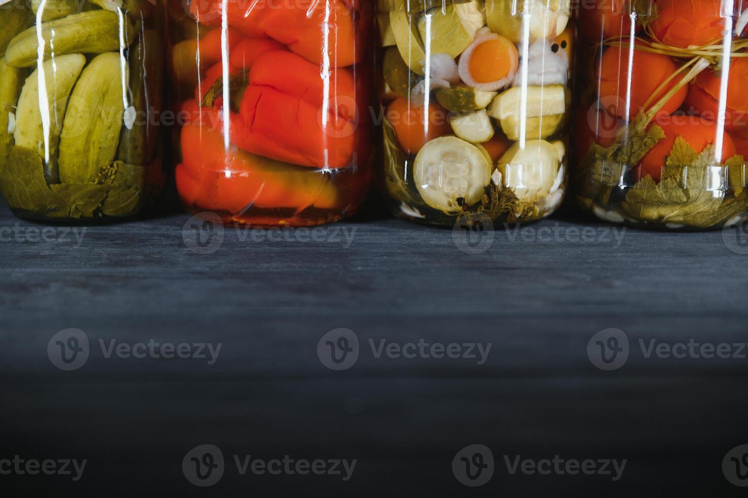 Canned cucumbers and tomatoes with craft lids on a wooden background. Cucumbers and tomatoes with place for text. Stocks of canned food. Harvest, stocks for the winter. photo