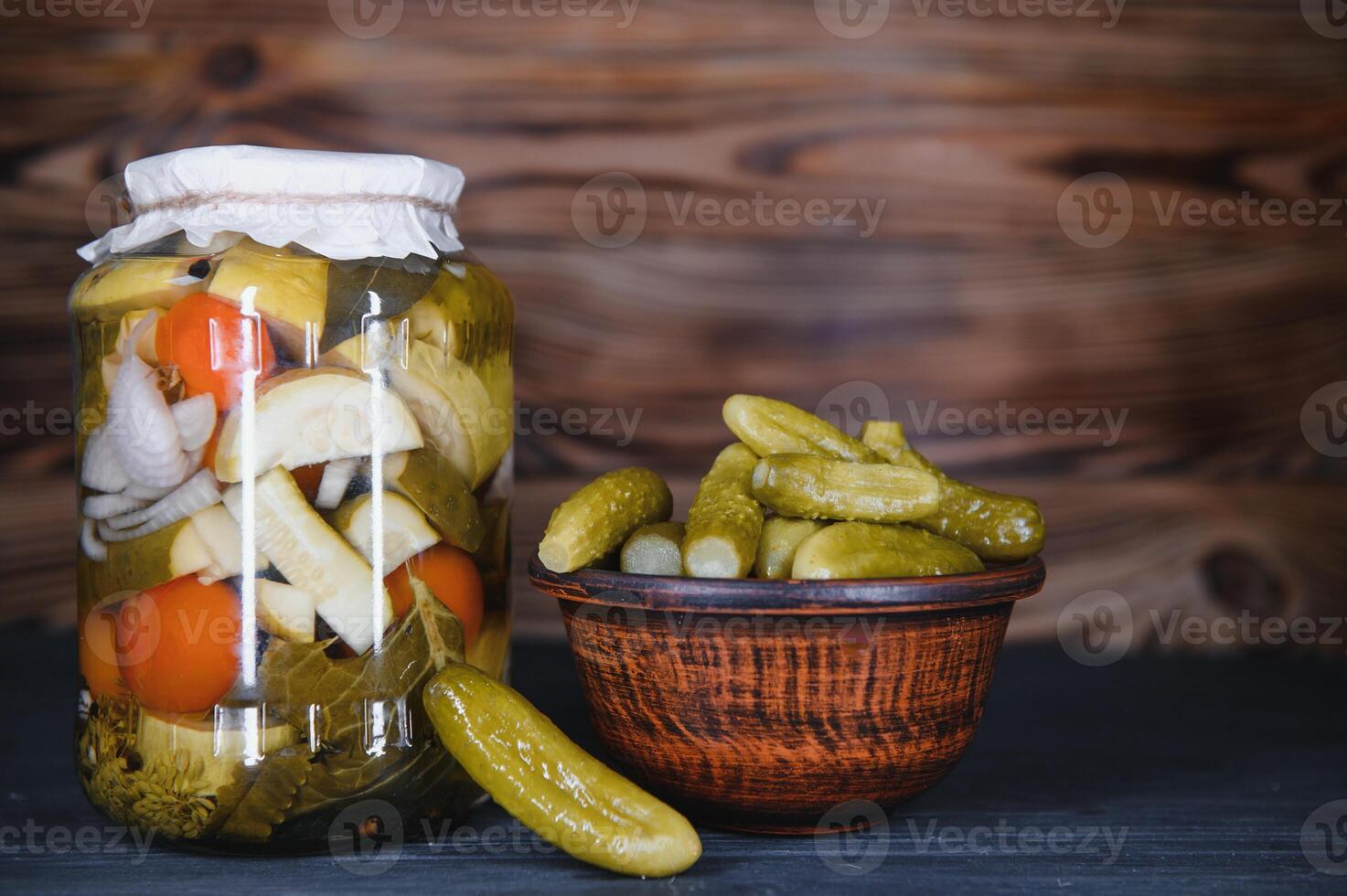 Glass jars with pickled cucumbers pickles, pickled tomatoes and cabbage. Jars of various pickled vegetables. Canned food in a rustic composition. photo