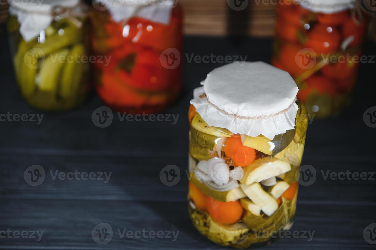 Jars of pickled vegetables on rustic wooden background photo