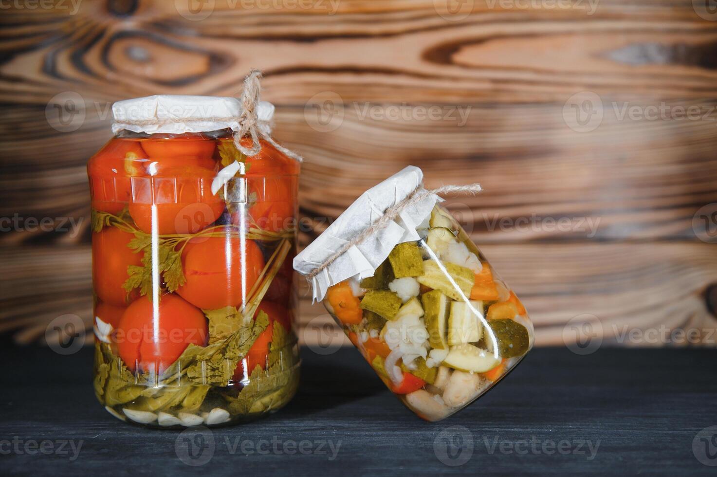 Jars of pickled vegetables on rustic wooden background photo