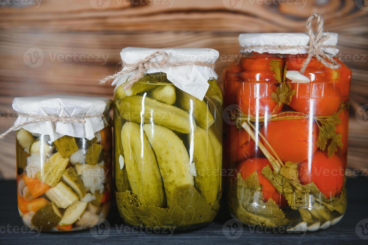 Jars of pickled vegetables on rustic wooden background photo