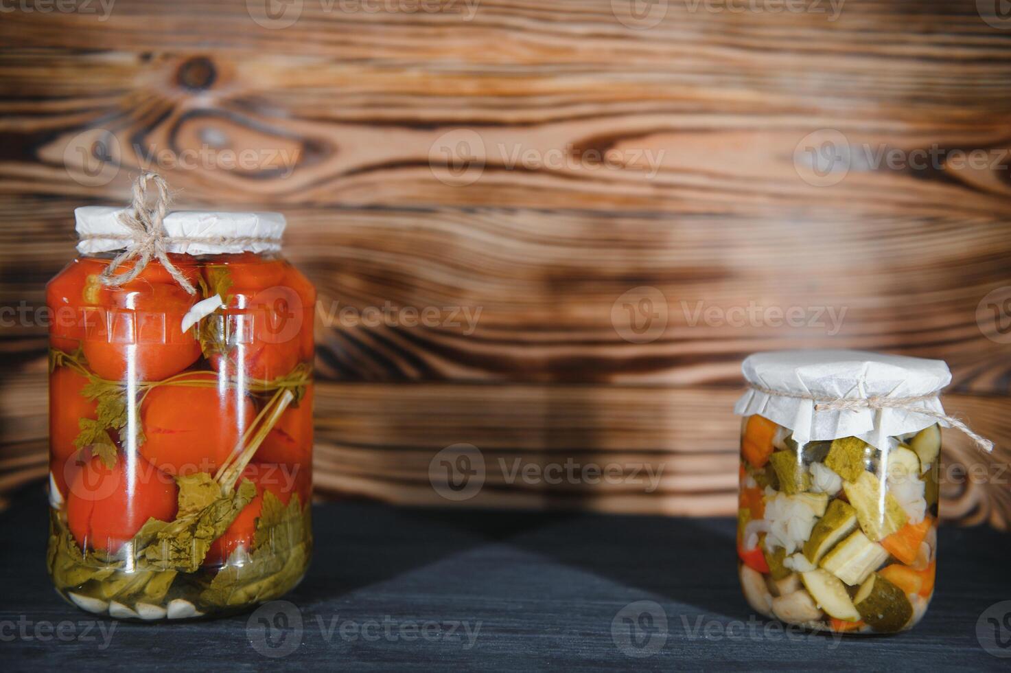 Jars of pickled vegetables on rustic wooden background photo