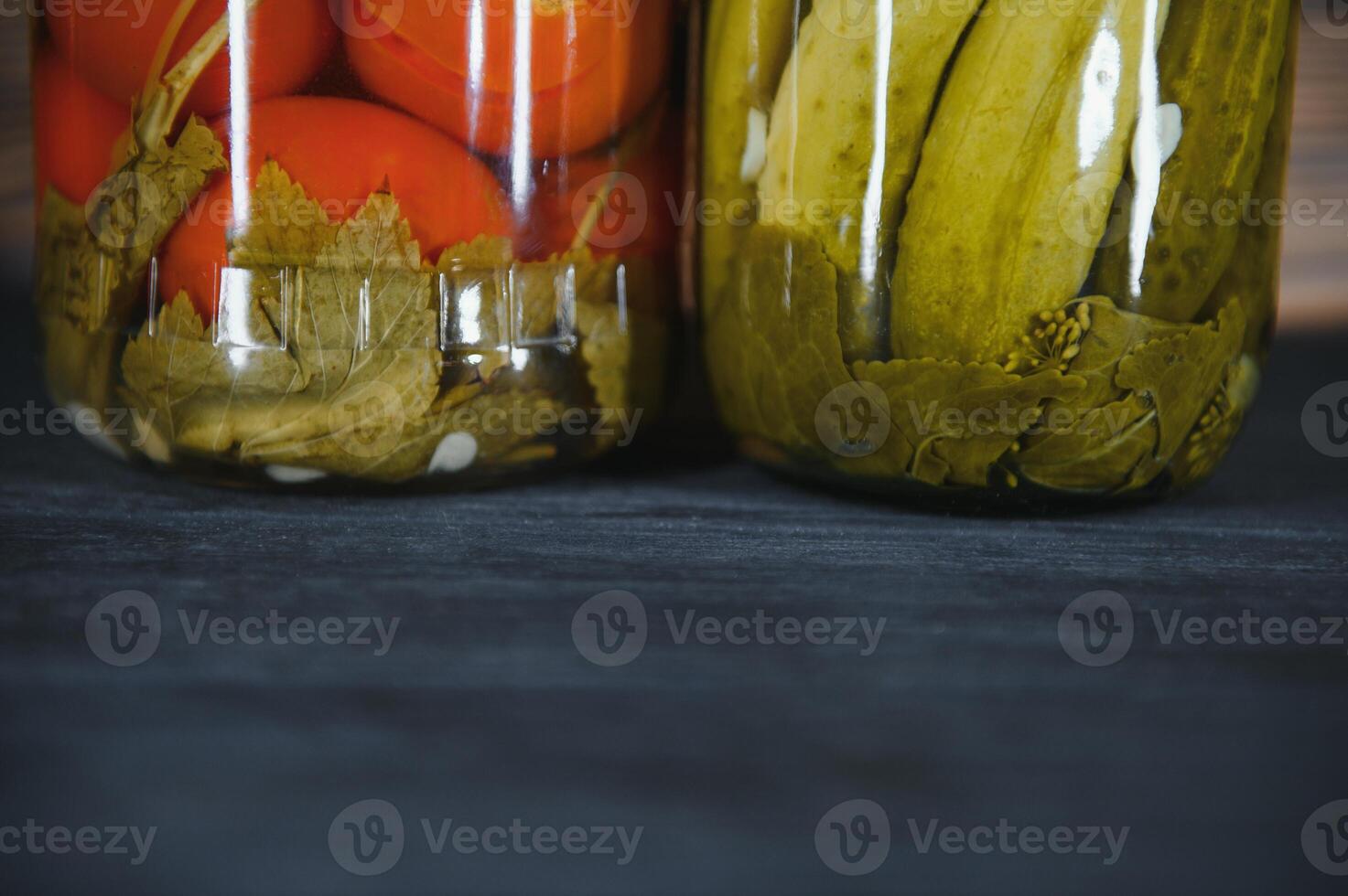 Jars of pickled vegetables on rustic wooden background photo