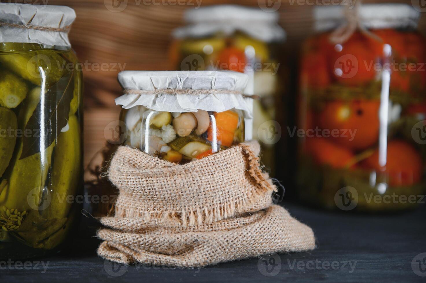 Canned cucumbers and tomatoes with craft lids on a wooden background. Cucumbers and tomatoes with place for text. Stocks of canned food. Harvest, stocks for the winter. photo