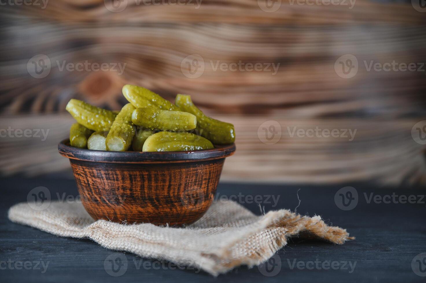 Pickled gherkins or cucumbers in bowl on wooden rustic table from above. photo