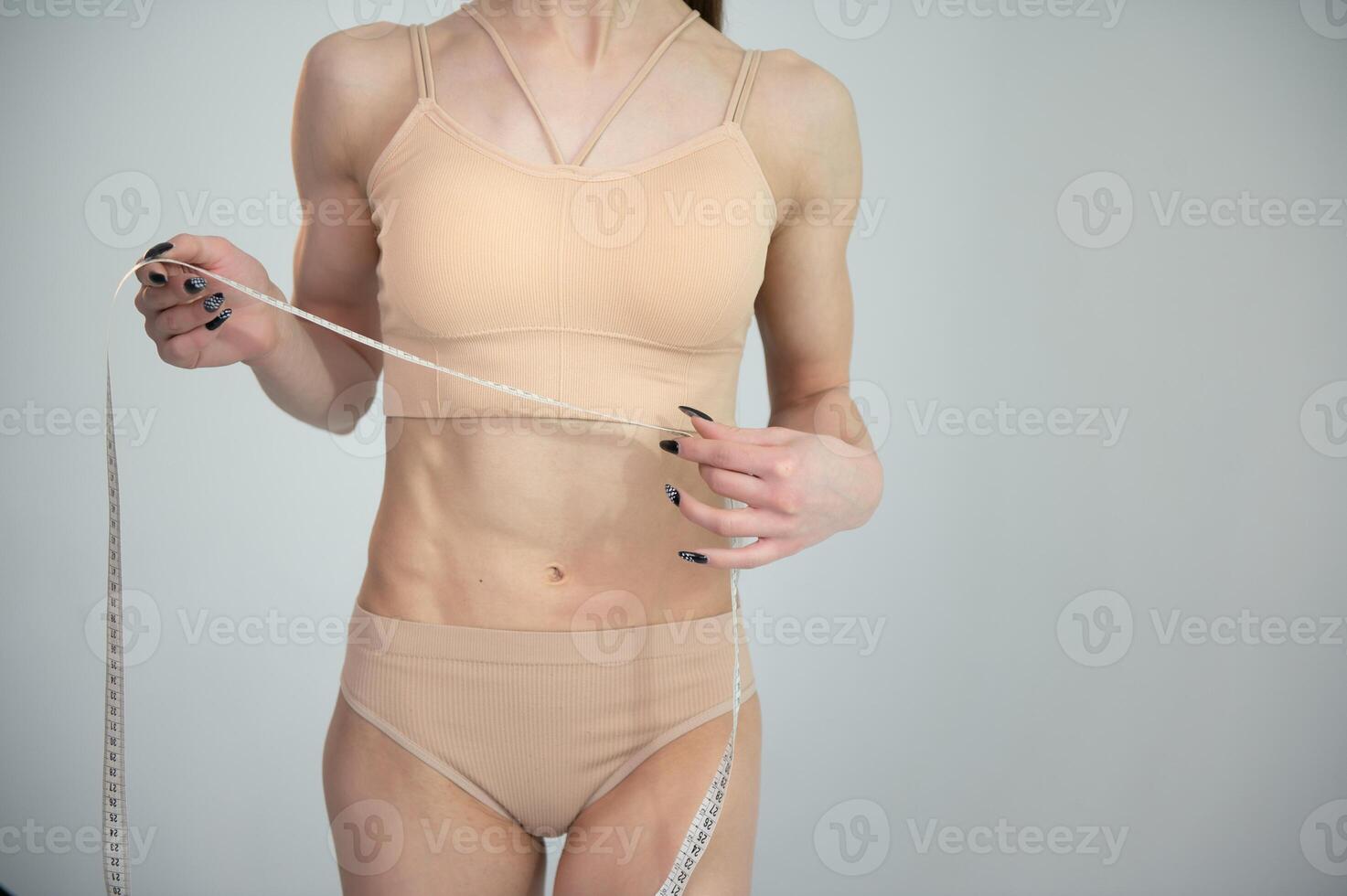 Flat stomach with measuring tape. Measuring a woman's waist with a measuring tape. photo