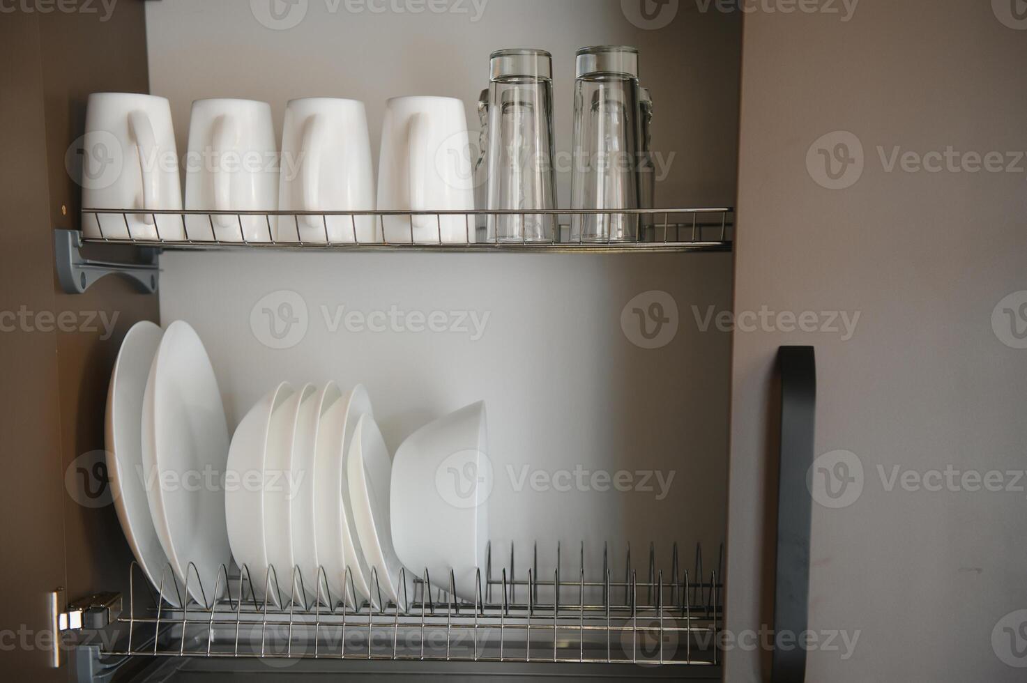 Open drawers with different plates and bowls in kitchen, closeup photo