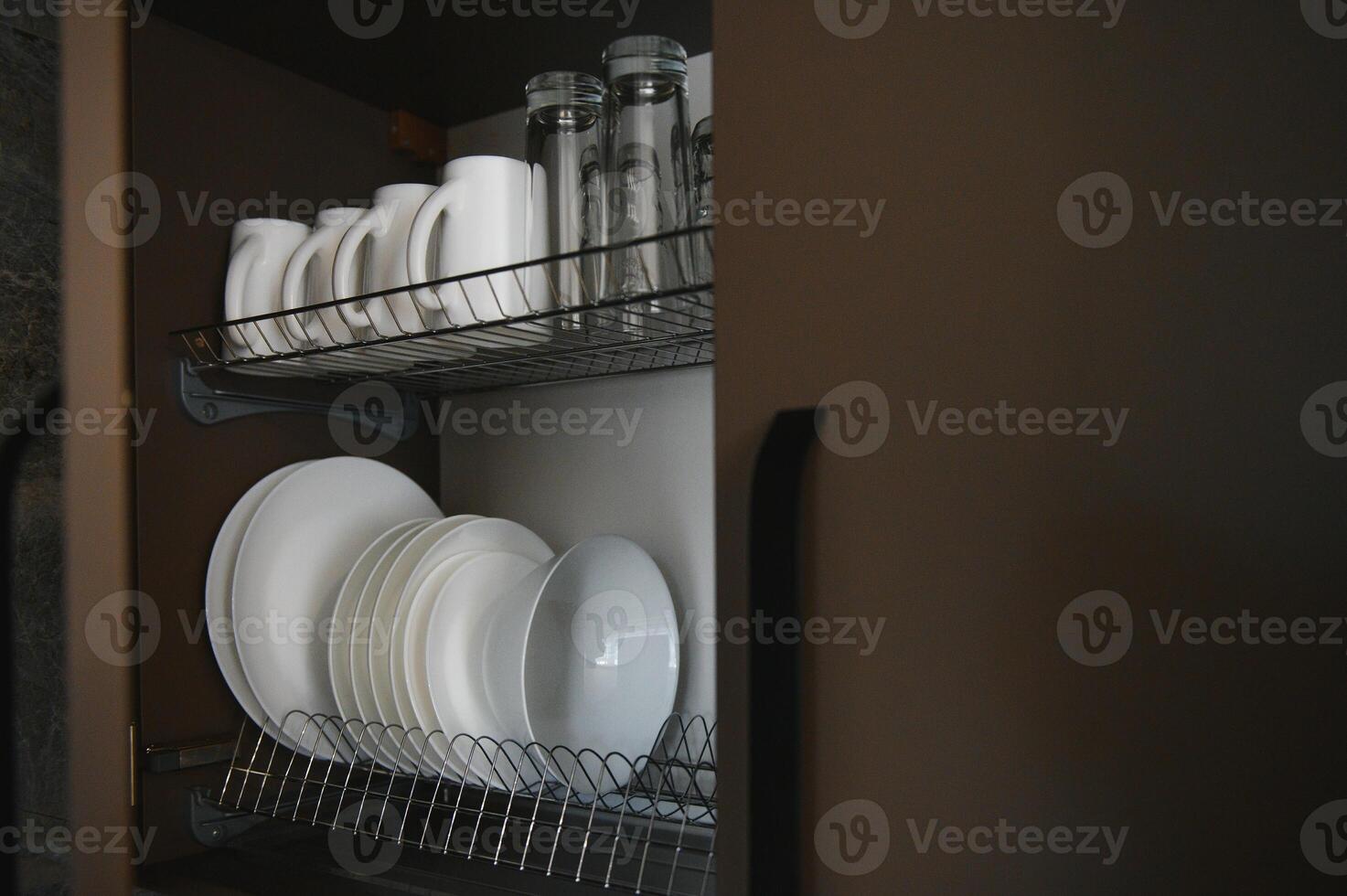 Open drawers with different plates and bowls in kitchen, closeup photo