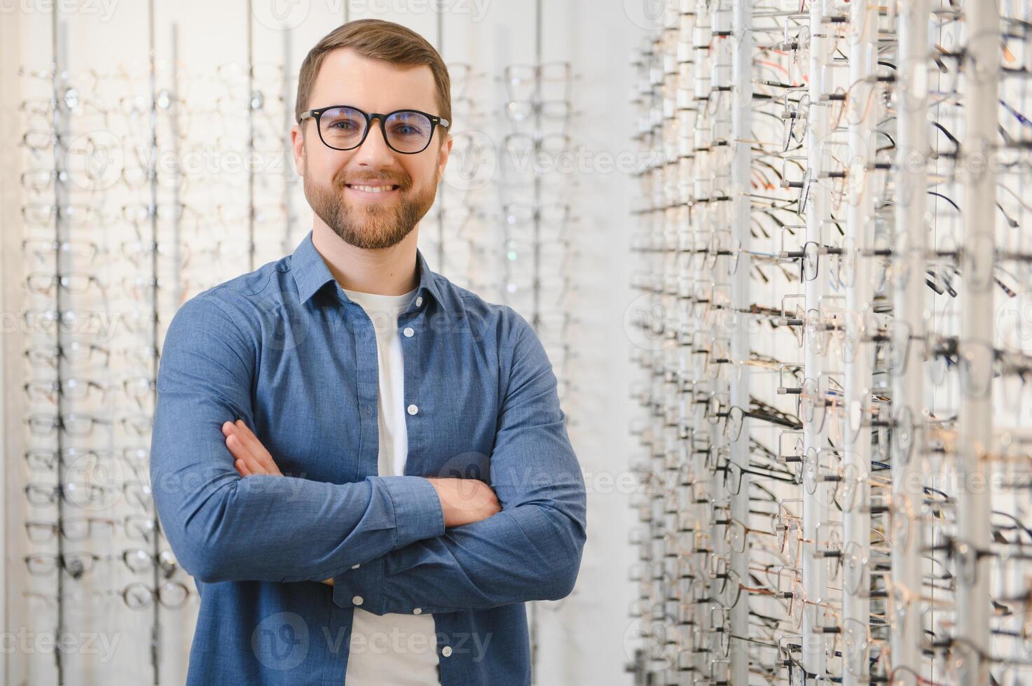 In Optics Shop. Portrait of male client holding and wearing different spectacles, choosing and trying on new glasses at optical store. Man picking frame for vision correction, closeup. photo