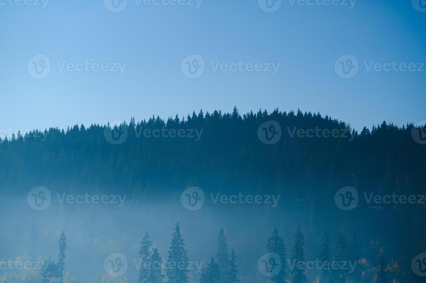 Mountain range with visible silhouettes through the morning blue fog. photo