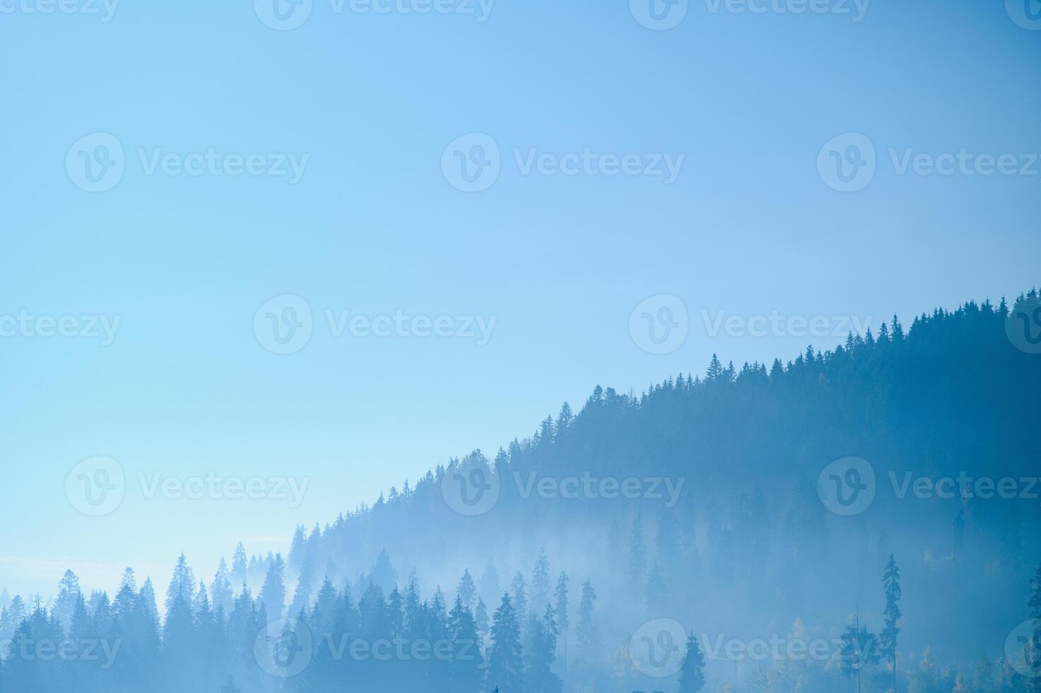 A close up view on the Alpine chains shrouded in the morning fog, seen from the top of Mittagskogel in Austria. Clear and sunny day. Sharp peaks around. Sun is shining above the high peaks. Serenity photo
