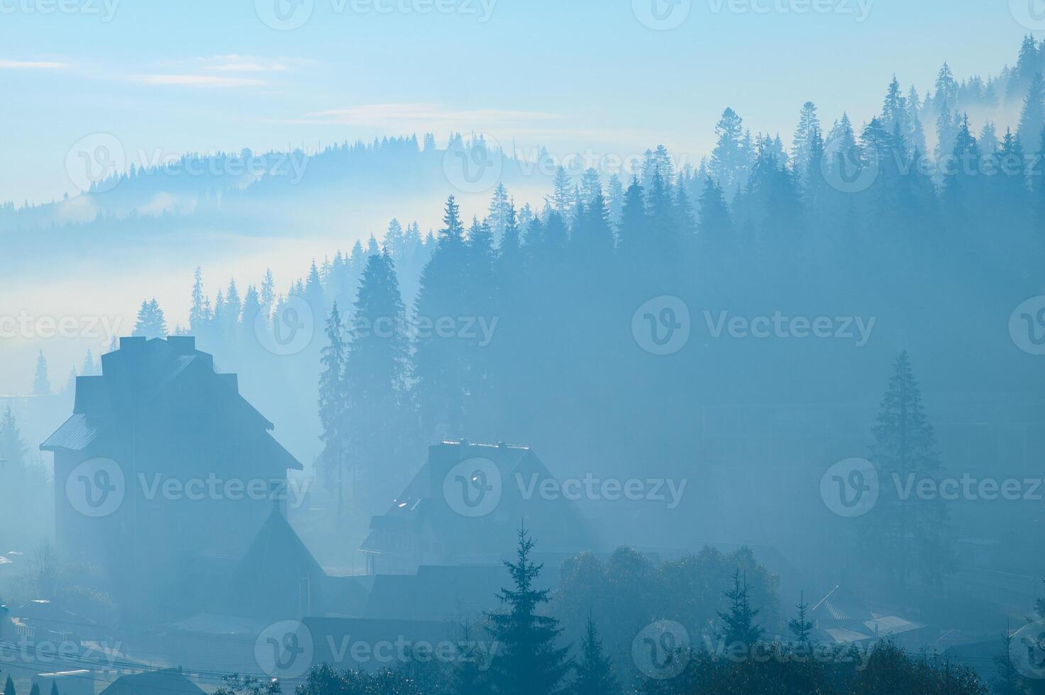 A close up view on the Alpine chains shrouded in the morning fog, seen from the top of Mittagskogel in Austria. Clear and sunny day. Sharp peaks around. Sun is shining above the high peaks. Serenity photo