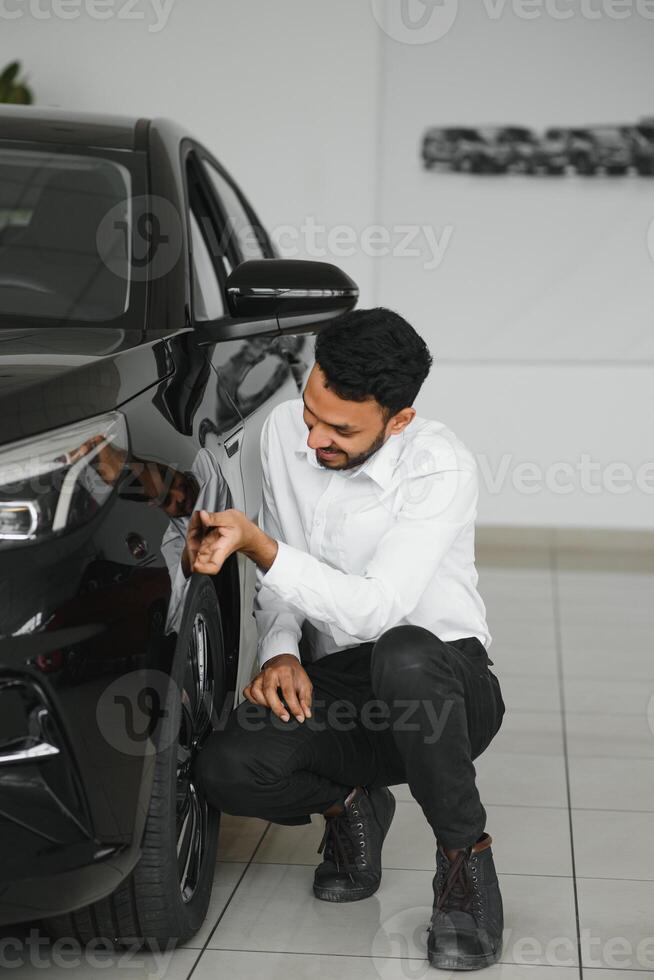 A young Indian man chooses a new car at a car dealership photo