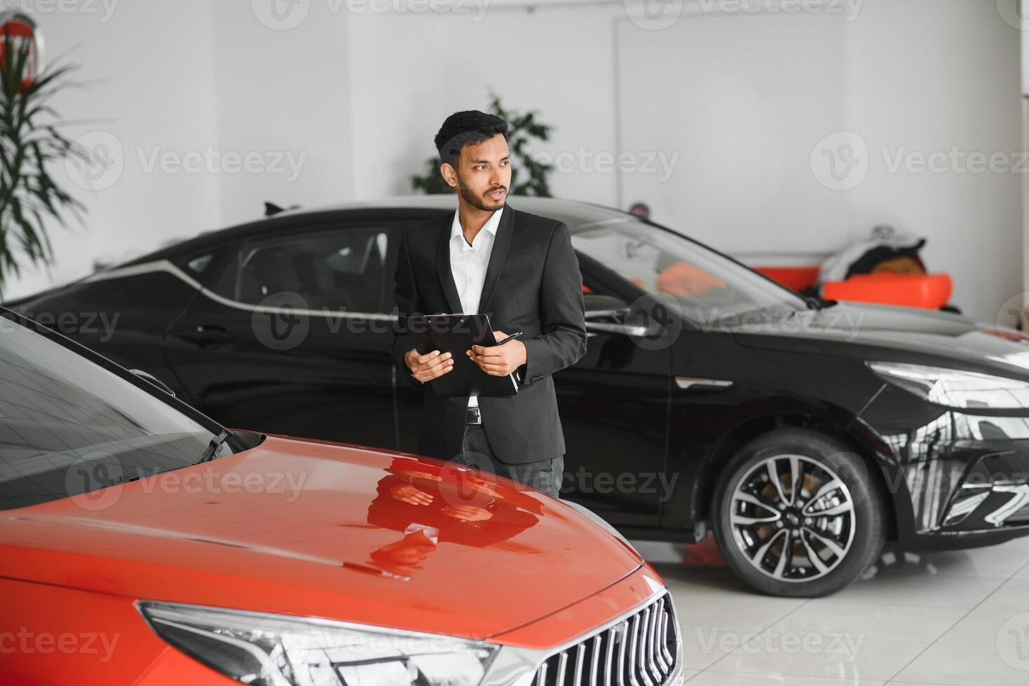 handsome indian salesman presenting new car to clients photo