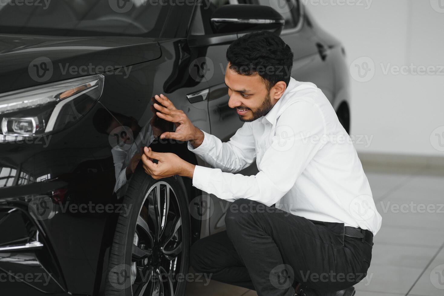 happy indian man buy new biodiesel eco automobile in lux showroom. photo