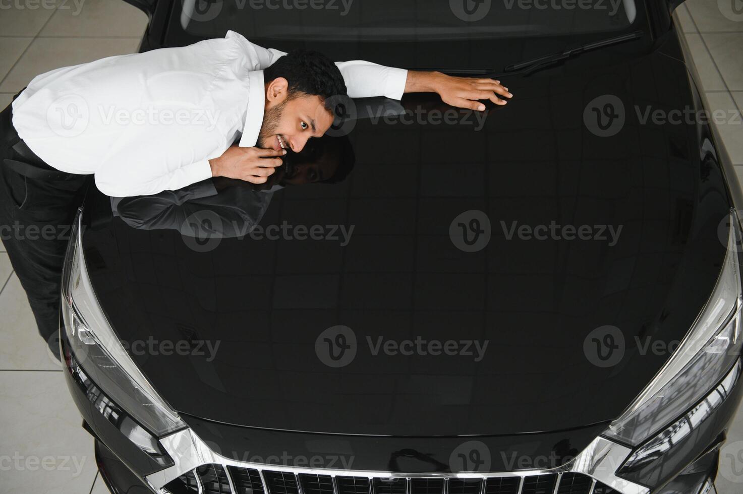 A young Indian man chooses a new car at a car dealership photo
