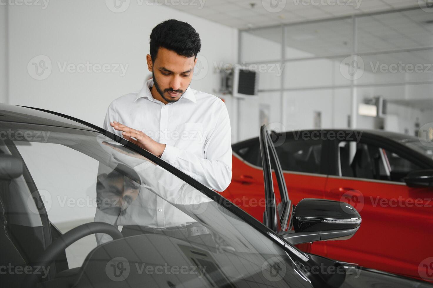 happy indian man checking car features at showroom photo