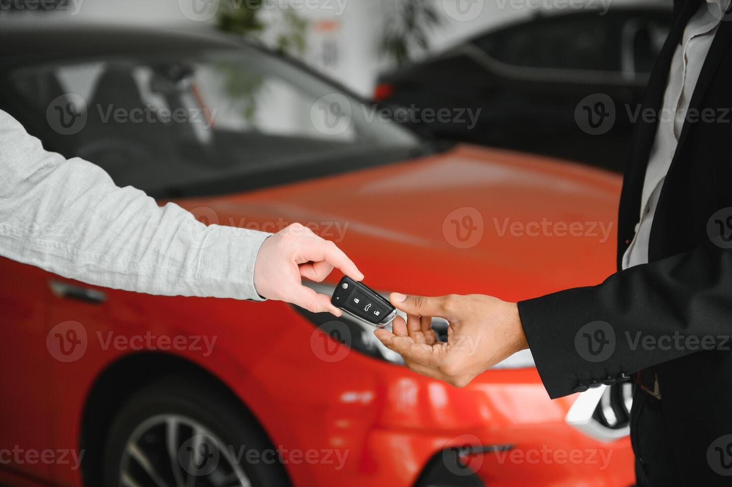 Indian auto dealer giving key of new car to crop male client in salon photo